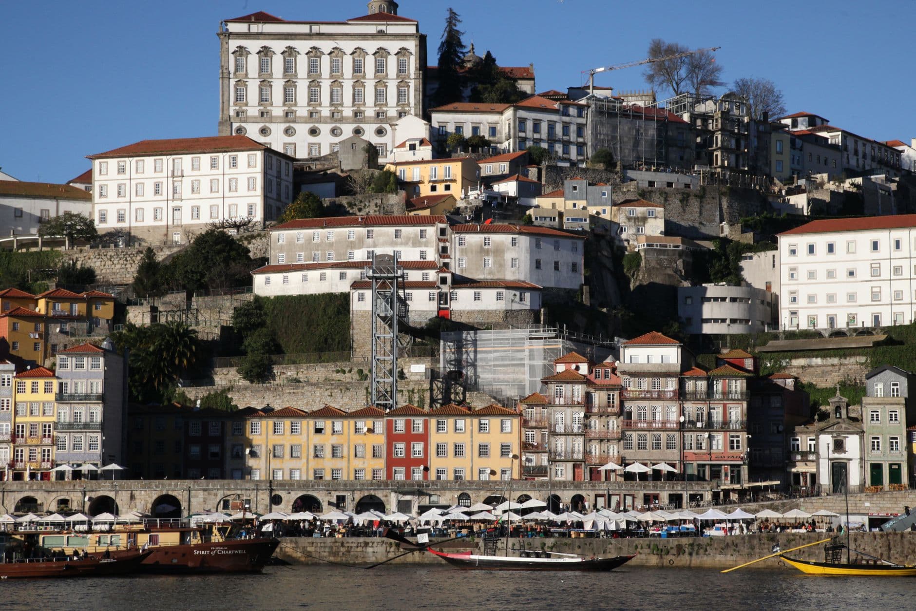Porto riverside at sunset with traditional rabelo boats and colorful buildings on hillside