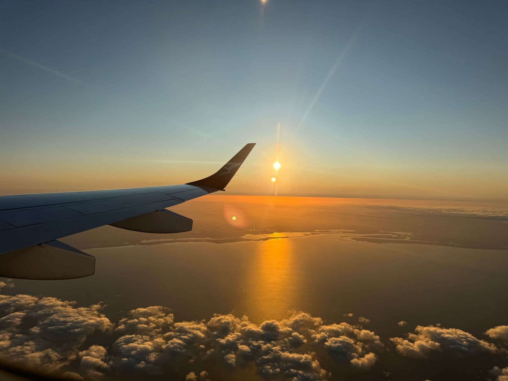 Sunrise view from airplane wing with golden light over clouds