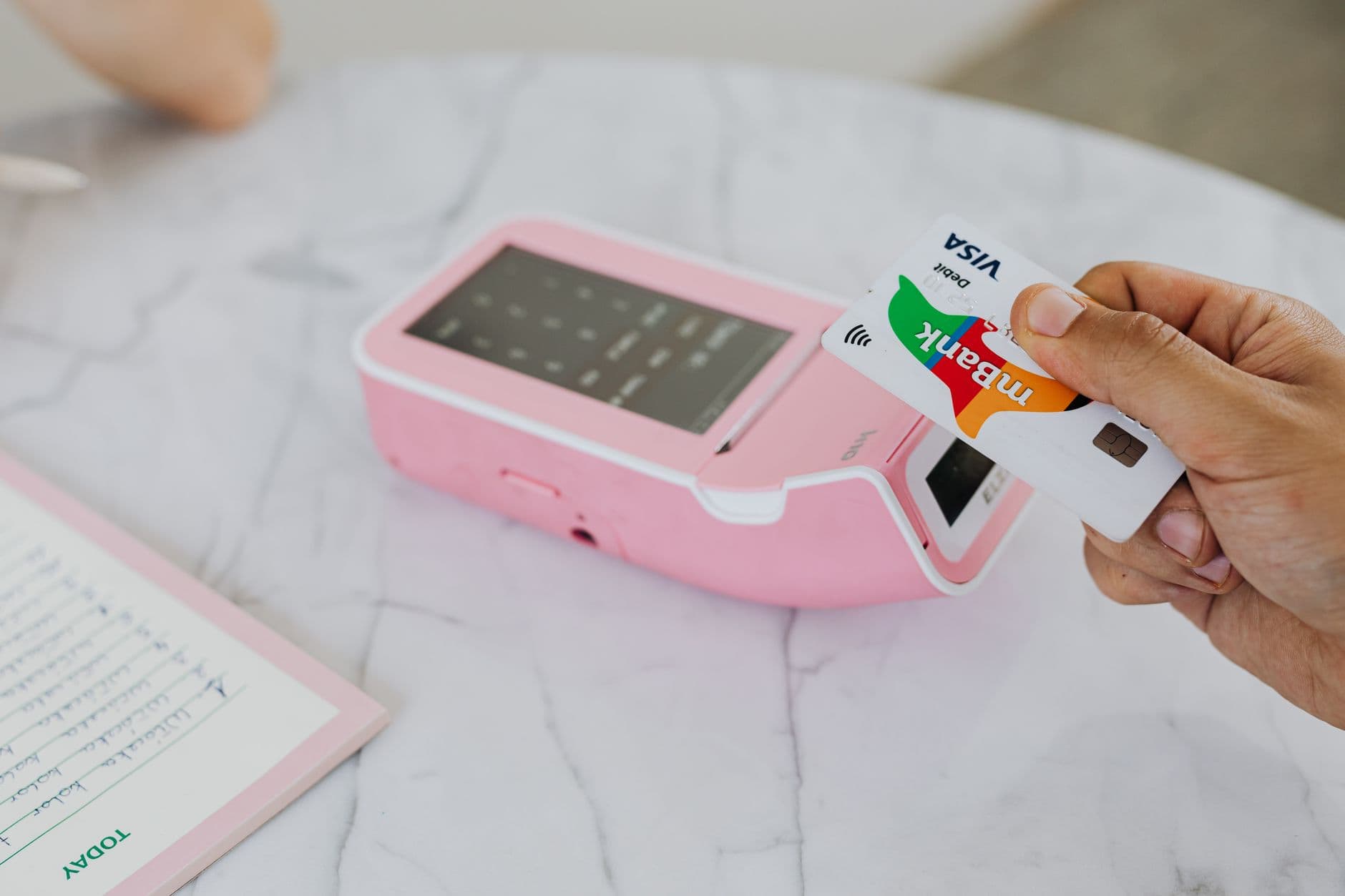 Person tapping credit card at payment terminal for travel rewards