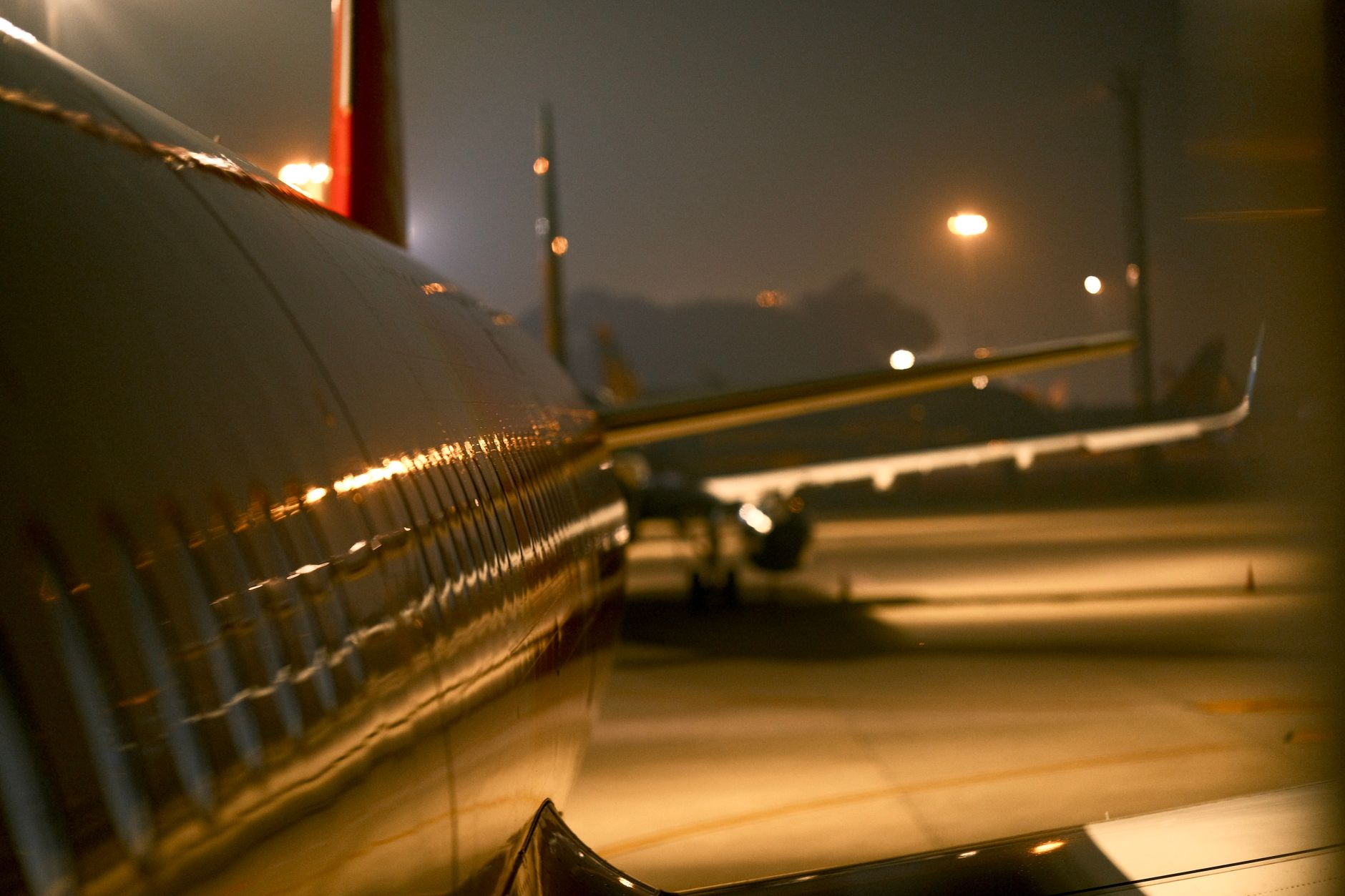 An aircraft at an airport terminal lit up at night, the quiet hours before a morning departure bank