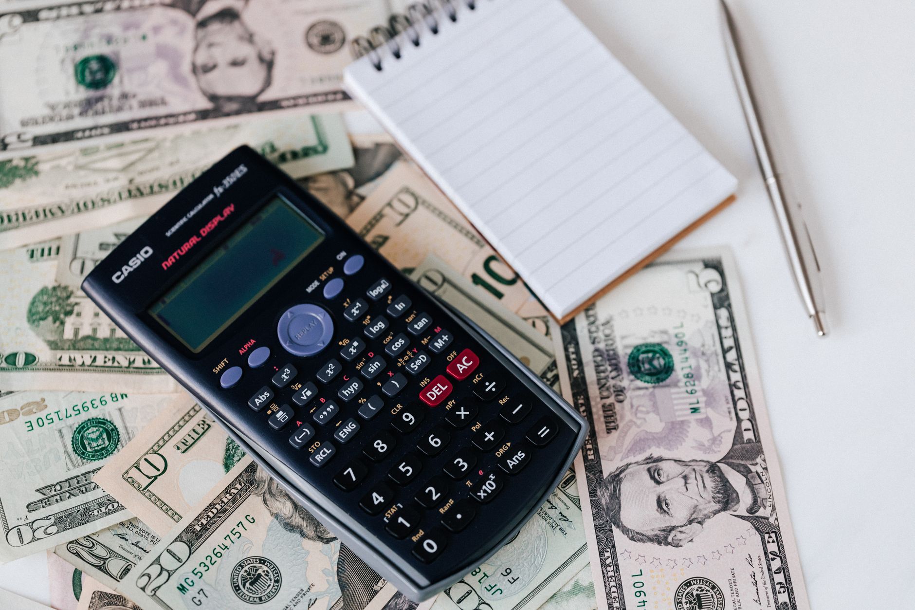 Budget calculator and travel money on a table, adding up the true cost of a cheap fare